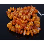 An unpolished butterscotch amber necklace as loosely graduated rough cut beads on a knotted string,