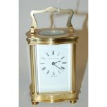 An early 20th century lacquered brass cased serpentine shaped carriage clock,