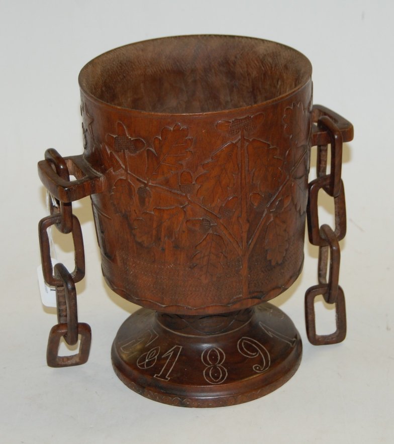 A large late Victorian treen pedestal goblet, having all-over carved leaf and acorn decoration,