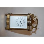 An early 20th century serpentine shaped lacquered brass cased carriage clock,