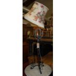 An early 20th century black painted wrought iron and copper standard lamp