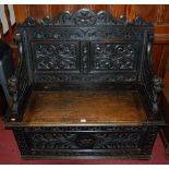 A late 19th century heavily carved and ebonised oak two panel boxseat settle,