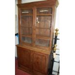 A late Victorian pitch pine bookcase cupboard, having twin door glazed upper section,