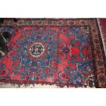 A Persian woollen red ground rug,