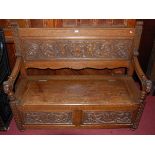 A circa 1900 heavily carved oak two panelled box seat settle, having lion mask carved terminals,