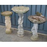 A collection of three various reconstituted stone garden pedestal bird baths