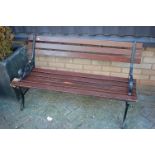 A black painted cast metal and stained wood slatted two seater garden bench, w.