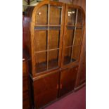 A 1930s oak double door glazed bookcase, over two lower cupboard doors with bakelite handles, w.