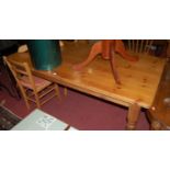 A modern pine round cornered farmhouse style kitchen table, raised on turned supports,