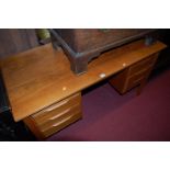 A 1960s teak kneehole writing desk, having six drawers, raised on square cut supports, w.