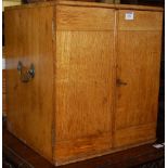 A circa 1900 light oak double door table-top cupboard, having brass carry handles, w.