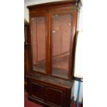 A Victorian mahogany round cornered bookcase cupboard, having twin door glazed upper section, w.