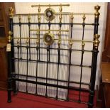 A Victorian black painted cast iron and brass double bedstead, having integral circular mirrors,