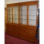 A pair of contemporary moulded oak display cabinets, each having twin glazed upper doors,