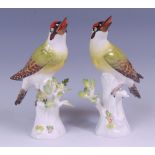 A pair of Meissen porcelain woodpeckers, each modelled upon treestumps, decorated in bright enamels,
