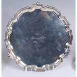 A George VI silver salver, having a raised and shaped border, on three scroll hoof feet,