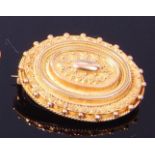 A Victorian yellow metal mourning brooch, of tiered oval form with filigree type decoration,