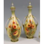 A pair of Royal Worcester porcelain twin handled vases and covers, each of slender baluster form,