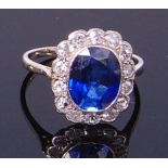 A white metal, sapphire and diamond set ring, arranged as an oval cut sapphire weighing approx 2.