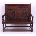 *A circa 1700 joined and later carved oak three-panel settle, having square cut arms,