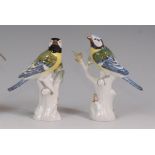 A pair of Meissen porcelain blue-tits, each perched upon treestumps, decorated in bright enamels,