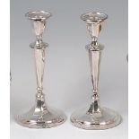A pair of silver pedestal candlesticks, each of octagonal faceted form on tapering columns,