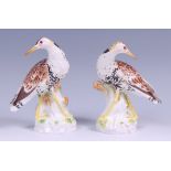 A pair of Meissen porcelain ruffs, each with polychrome painted plumage, on stump bases,