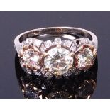 A white metal diamond three stone ring, the centre claw set brilliant weighing approx 1.