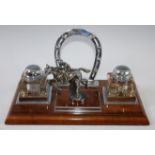 An early 20th century walnut and chrome desk stand surmounted with a horseshoe and racehorse with