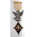 A mid-20th century Masonic jewel having a silver gilt clasp on a yellow ribbon with a silver eagle