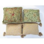 Four feather filled cushions, two being gross point embroidered, 47 cm and 55 cm respectively,