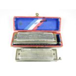 A boxed Hohner The Super Chromonica chromatic harmonica together with one other