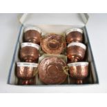 A 1930s boxed set of six copper and brass tea cups and saucers, with porcelain bowls, each element