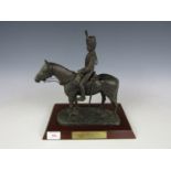 A cold cast bronze sculpture of a Royal Horse Artillery Trooper and mount, on wooden platform base