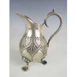 An Edwardian silver cream jug, of baluster form with scroll handle, above three cast feet, punched