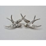 A Victorian white metal and paste brooch in the form of a pair of volant swallows, the birds each