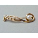 A 9ct gold and pearl bar brooch, of scrolling ribboned form encircling a single pearl sphere