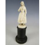 A finely carved ivory statuette of an 18th Century peasant girl, on a turned ebony socle, 19th