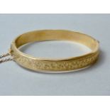 A 9ct gold hinged bangle, the face foliate engraved, 19.5g