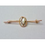 A vintage baroque pearl bar brooch, the stone being wire wrapped and pellet set within an annulus,