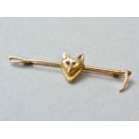 A 9ct gold bar brooch in the form of a riding whip centrally surmounted by a fox mask, the eyes