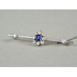 A high carat white metal, diamond and sapphire bar brooch, with central flower head cluster