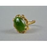 A jade and yellow-metal cocktail ring, the cabochon claw set within a stylized pelleted and cusped