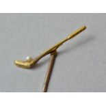 A yellow metal novelty stick pin modelled in the form of a golf club with seed pearl golf ball,