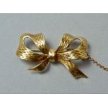 A mid 20th Century 18ct gold brooch in the form of a bow, with chased decoration to the face, 4