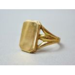 A yellow metal signet ring, having a rectangular face with canted corners, supported by