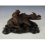 A Chinese carved hardwood figure of a boy and a water buffalo, with inset glass eyes and bone teeth,