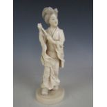 A Meiji Japanese ivory okimono carved in depiction of a lady walking in geta carrying a parasol,