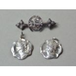 A pair of Edwardian Art Nouveau silver pendants, each in the form of a shaped plaque bearing the