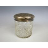 A silver topped cut glass toiletry jar